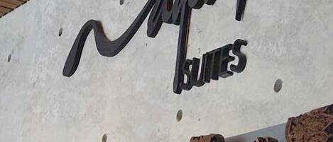 Una pared con un letrero que dice "Jampii Suites" y una exhibición de diversas tallas de madera.