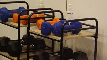 A gym with weightlifting equipment including dumbbells and medicine balls on shelves.