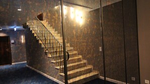 A staircase with a metal railing leading to a landing. The walls are covered in a textured, dark-colored material. - Hotel Tari (Hoechberg)