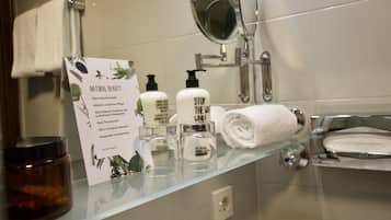 Un baño con un estante de vidrio que contiene artículos de tocador, un espejo y un cartel sobre productos de belleza naturales.