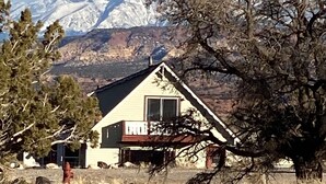 Une maison avec un toit en pente, une cheminée et une véranda.