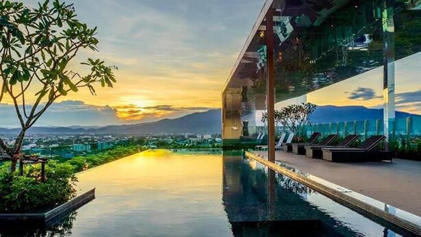 A modern infinity pool with a clear view of the city and mountains in the background.