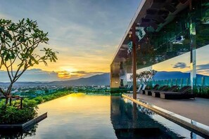 A modern infinity pool with a clear view of the city and mountains in the background.