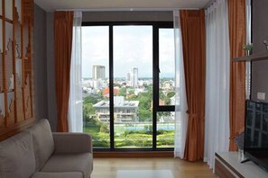 A modern living room with a large window, a sofa, and a flat-screen TV.