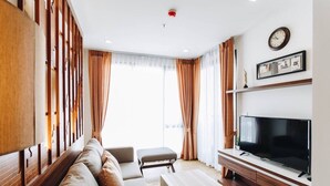 A modern living room with a sofa, a coffee table, a TV, and a wooden partition.