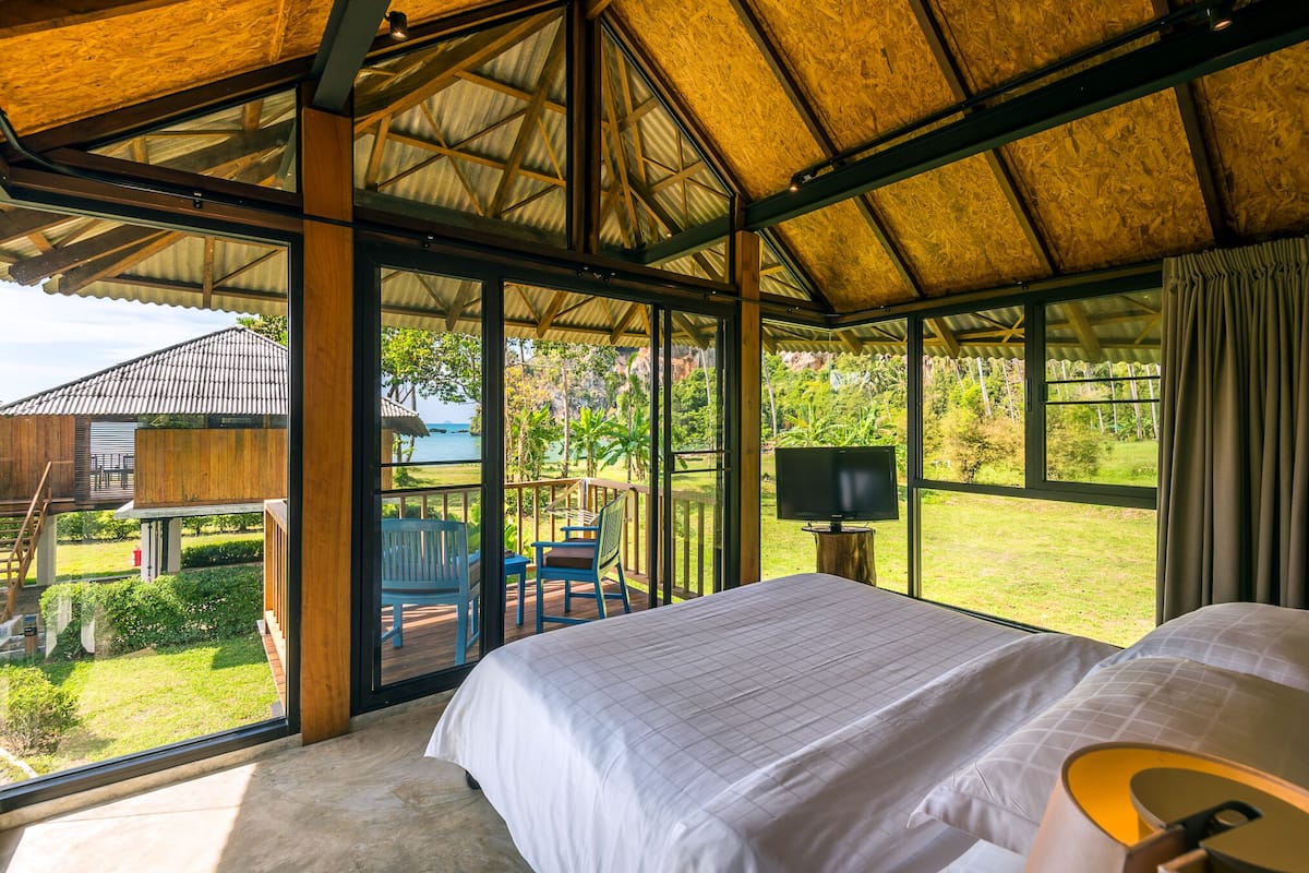 Un dormitorio amplio con una cama grande, televisión y vistas al jardín y al exterior.