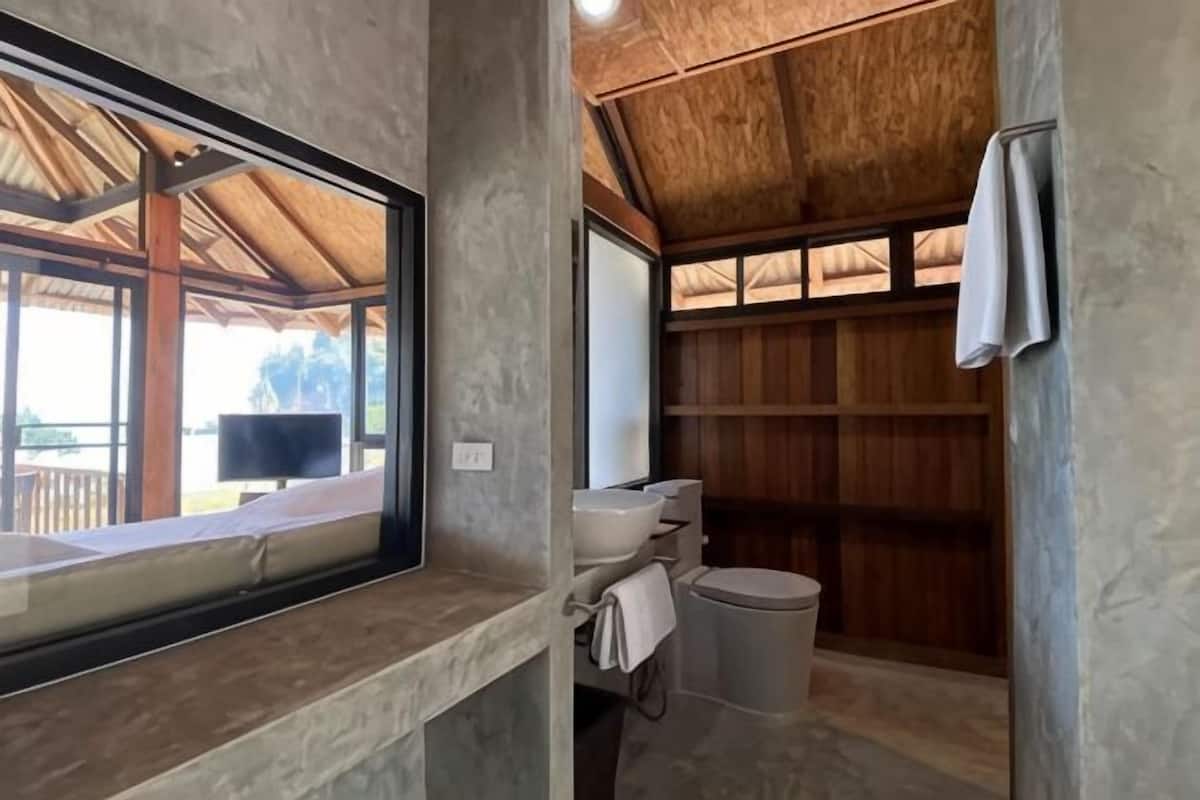 Un baño con pared de concreto, techo de madera, una ventana y un perchero.