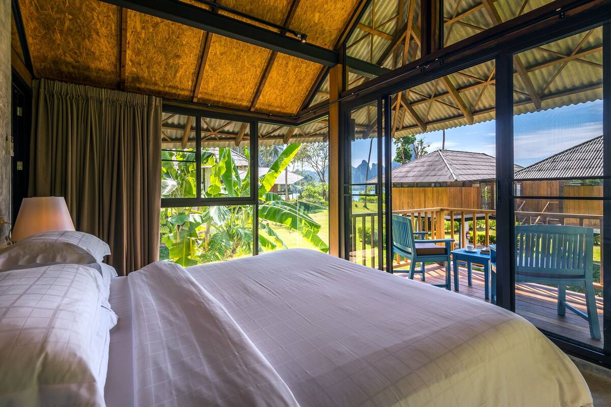 Una habitación con una cama grande, una mesa, sillas y vistas al exterior.