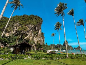 A tropical resort with a pool, palm trees, and a mountain backdrop.