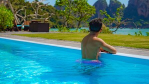 Un homme dans une piscine, avec vue sur un paysage montagneux et un ciel dégagé.
