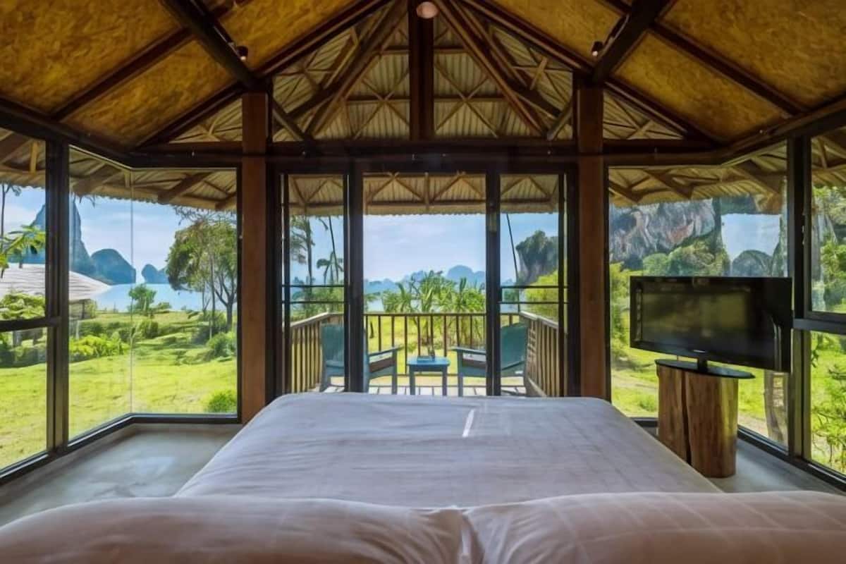 Una habitación con cama, televisión y balcón con vistas al paisaje.