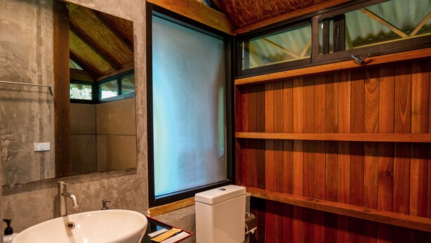 Ein Badezimmer mit einem großen Waschbecken, Toilette und Holzvertäfelung.