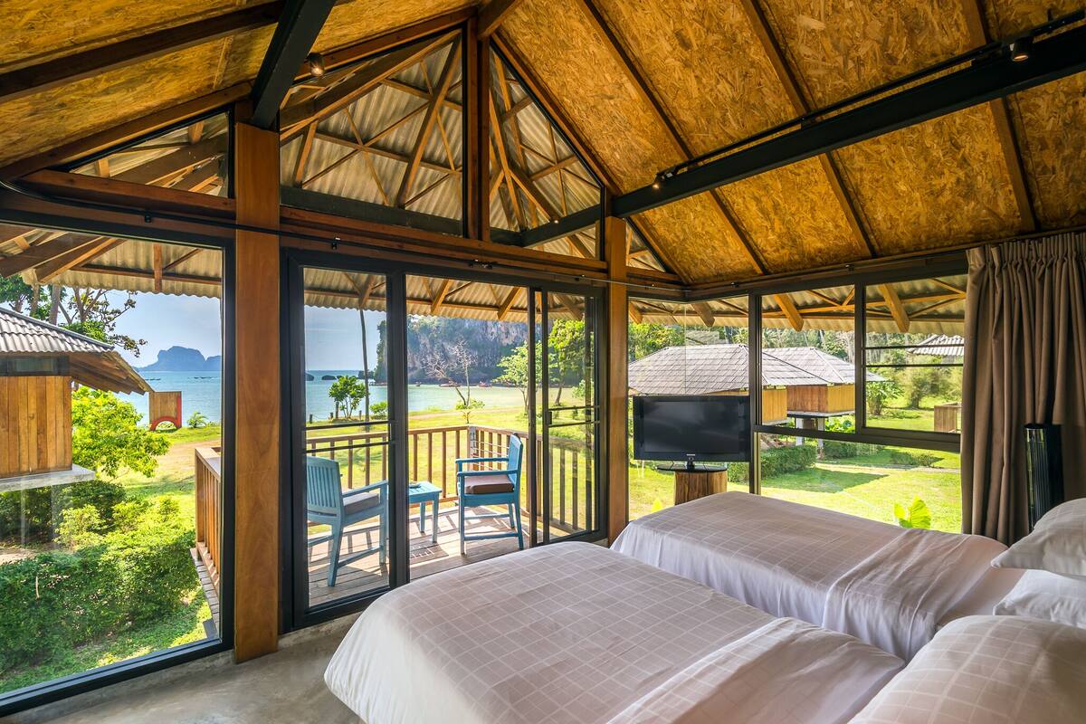 Una habitación con ventanas amplias, televisor y vista al mar.