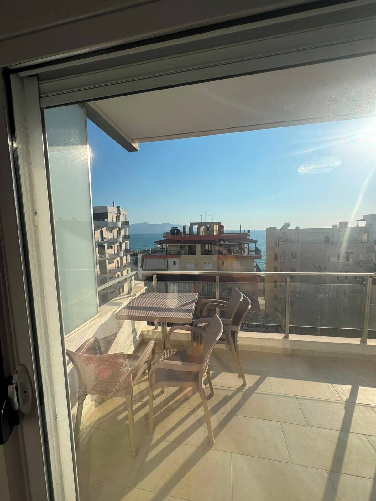 Un balcón con mesa y sillas, con vistas a la ciudad y al mar.