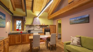 Una cocina acogedora con armarios de madera, una mesa de comedor con sillas y un sofá verde.