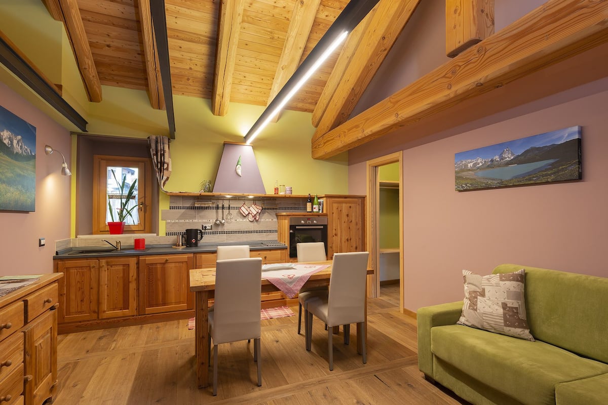 Eine gemütliche Küche mit Holzausbau, einem Esstisch mit Stühlen und einem grünen Sofa.