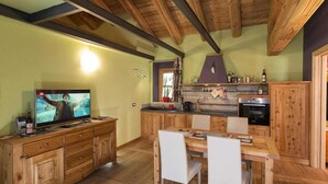 Una cocina rústica con armarios de madera, una mesa de comedor y un televisor mostrando una película.