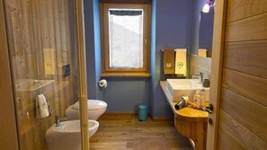 A compact bathroom with a wooden floor, a toilet, a sink, and a shower area. - Agriturismo Gli Elfi (Saint-Christophe)