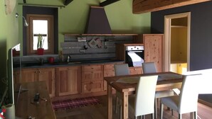 Una cocina con armarios de madera, una mesa de comedor y una estufa.