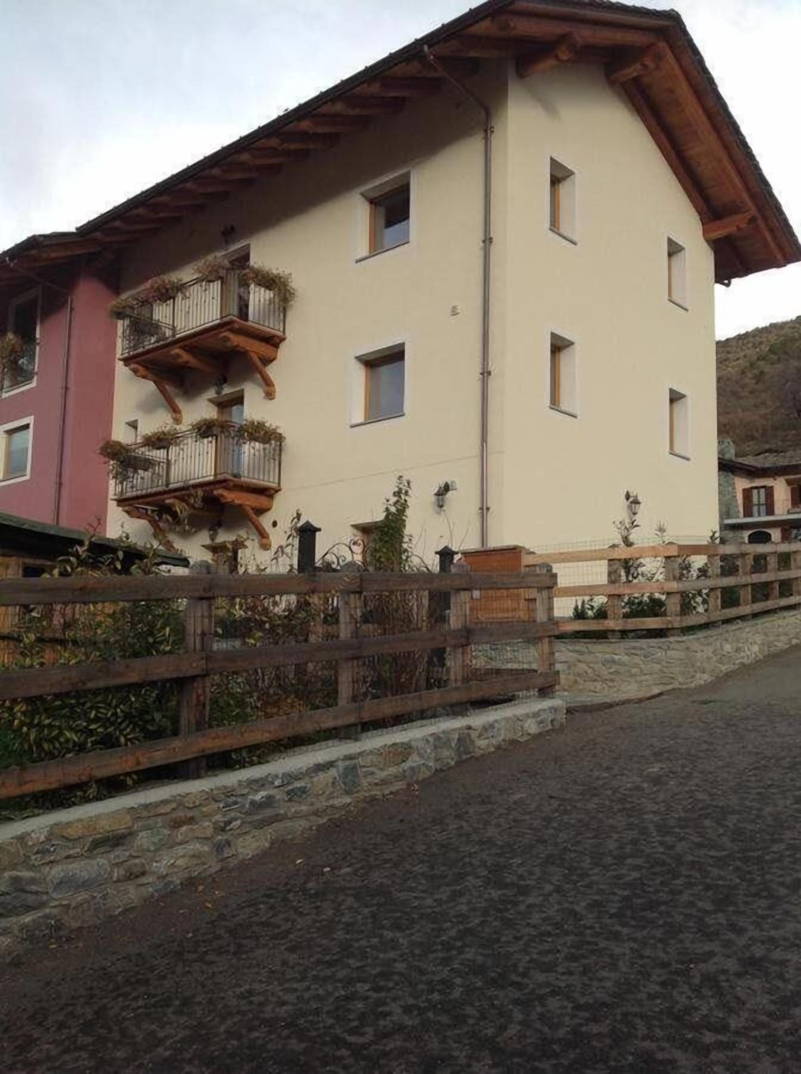 A multi-story building with balconies, a stone wall, and a cobblestone street.