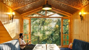 Ein Holzblockhaus-Interieur mit großem Fenster, einem Tisch und zwei Sofas.