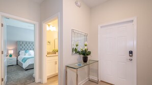 Un couloir comprenant un lit, une table de chevet et un miroir agrémenté d’une plante en pot.