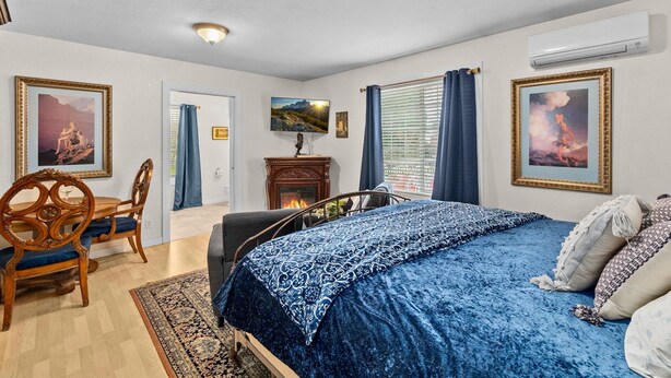 A bedroom with a bed, a wooden chair, a fireplace, and framed pictures on the wall. - Parrish Room at  BNB (Yelm)
