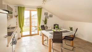 A dining area with a table set for four, chairs, a potted plant, and a view of the outside. - Ferienparadies Reifnhof (Riedering)
