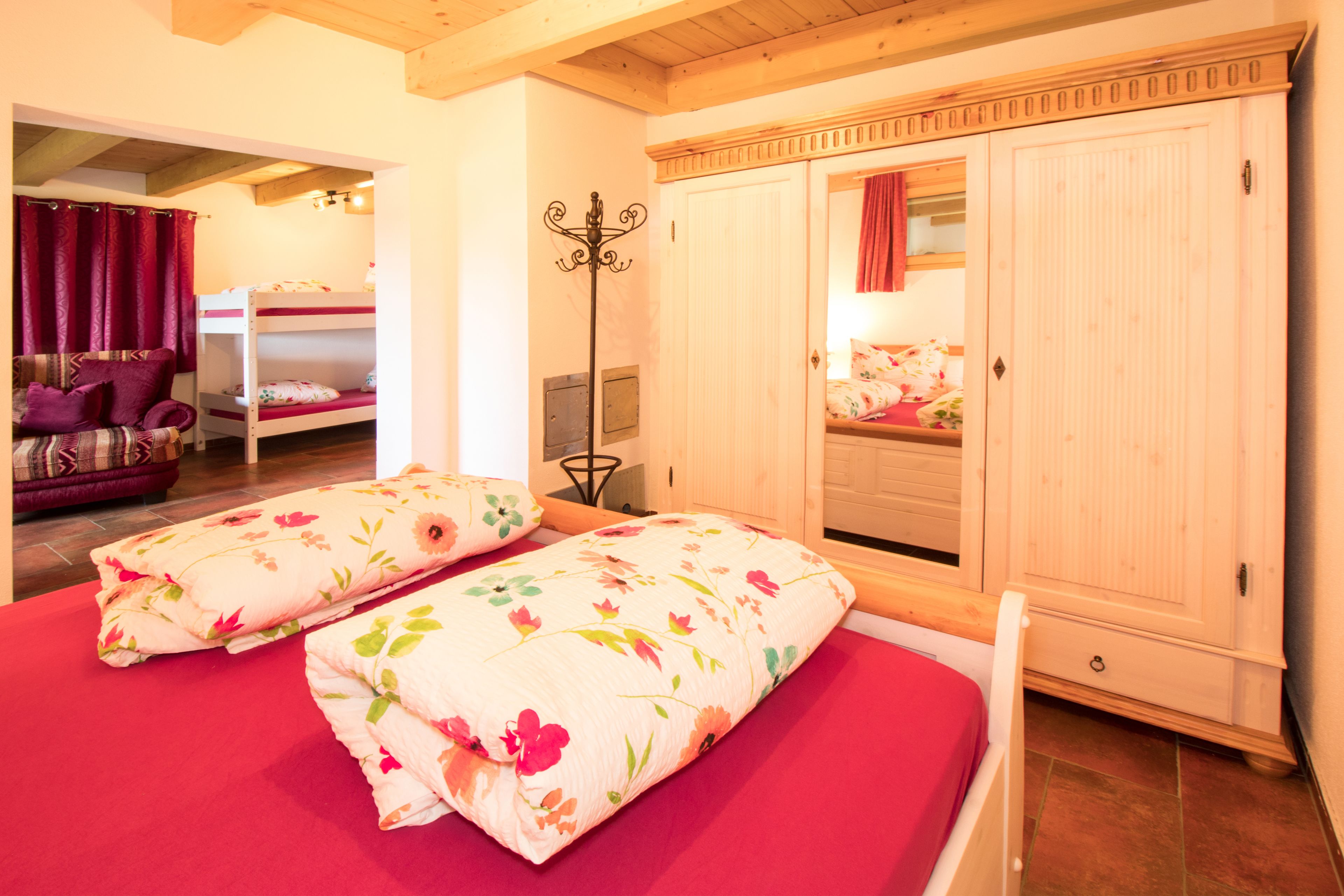 Un dormitorio con dos camas, un armario, un espejo y un perchero.