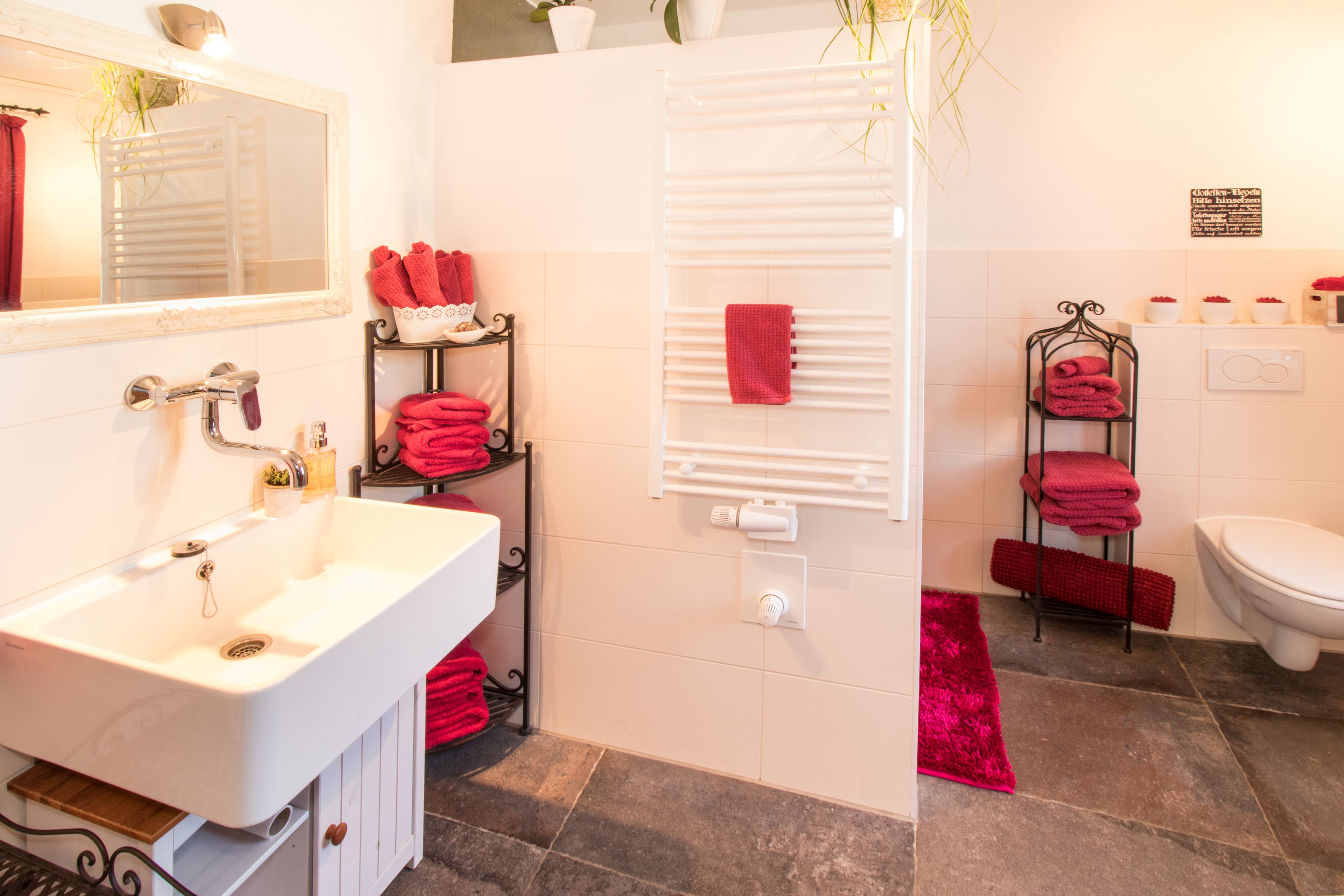 Une salle de bain avec un lavabo blanc, un miroir, un porte-serviettes, des toilettes et un espace douche.