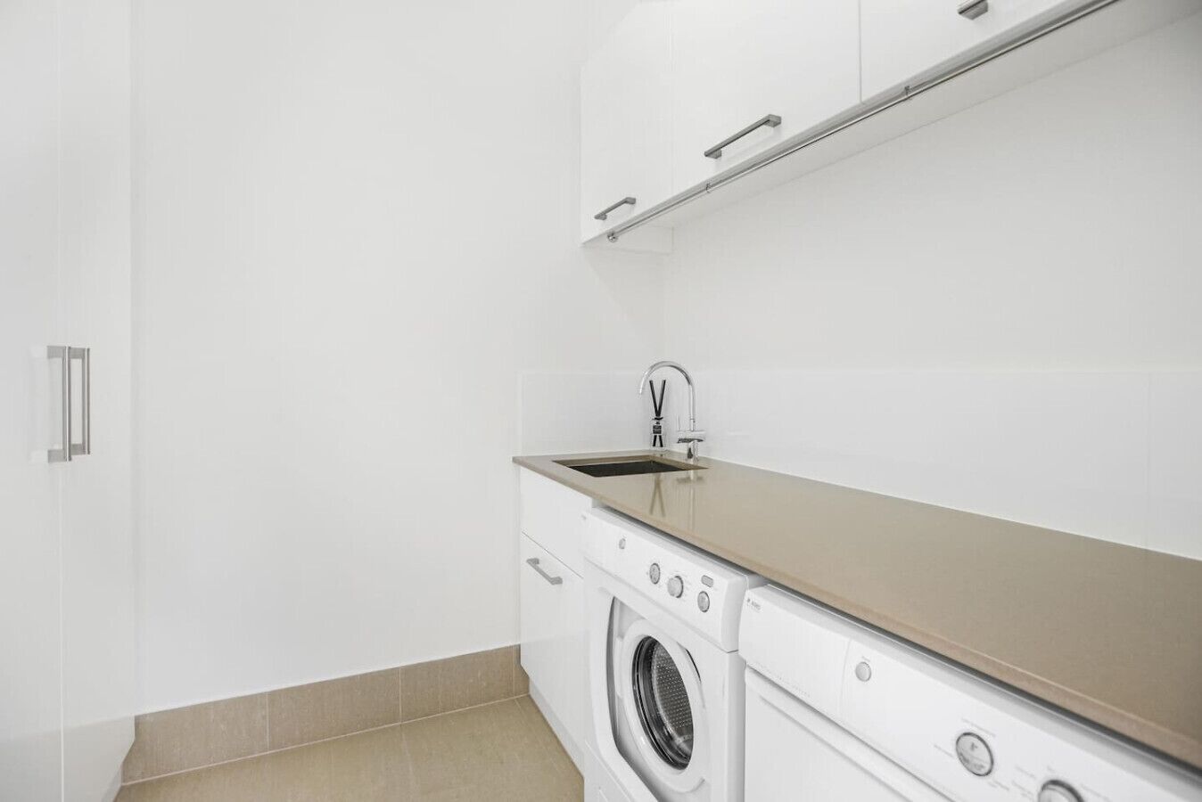 A compact laundry area with a washing machine, a sink, and a cabinet above the sink.
