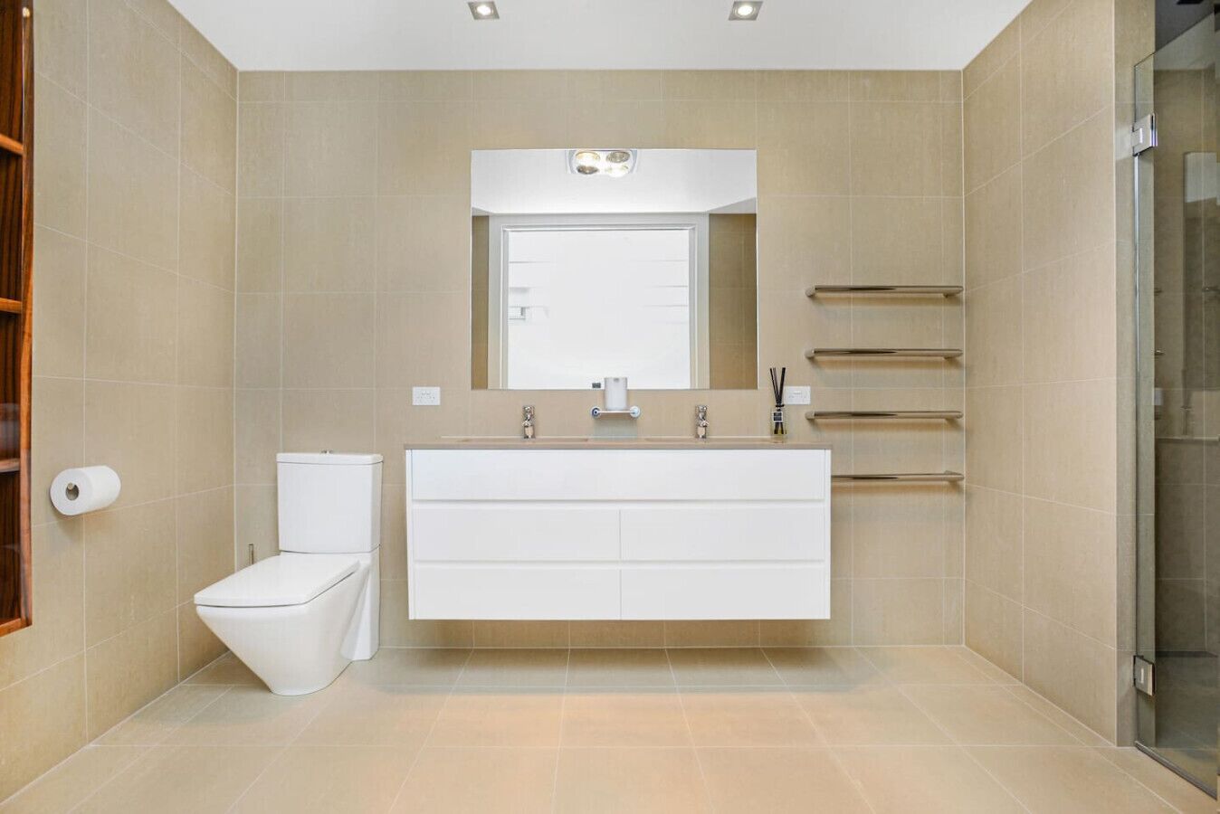 Een moderne badkamer met een wit toilet, een ruime wastafel met spiegel en een douchecabine van glas.