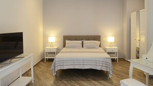 A neatly arranged bedroom with a bed, bedside lamps, a TV, a dresser, and a mirror. - B&B Fronte del Porto (Salerno)