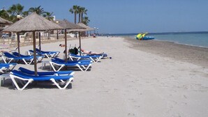 A beach with sun loungers and thatched umbrellas, a clear sky, and a calm sea. - Spacious 3-bed, 2-bath apartment with balcony, frontline golf and lake views (Torre-Pacheco)