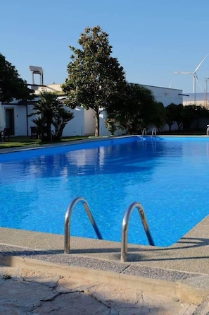 Une piscine avec des échelles en métal, entourée d’un bâtiment et d’arbres.