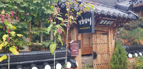 A traditional Korean building with a wooden exterior, a black tiled roof, and a mailbox labeled "MAIL".
