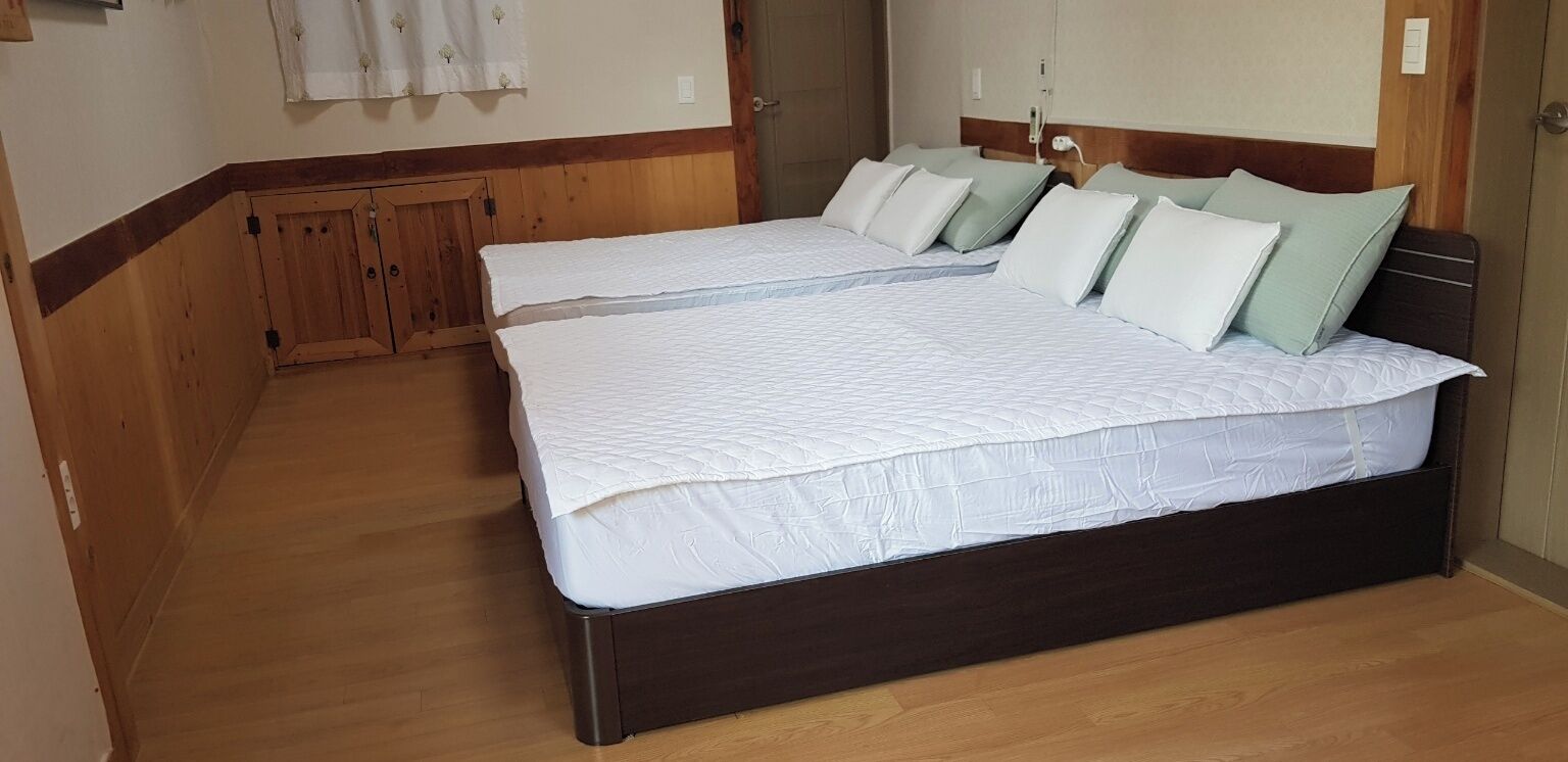 Un dormitorio con dos camas, suelo de madera y un armario de madera.