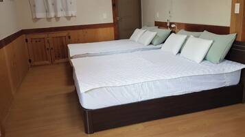 Un dormitorio con dos camas, suelo de madera y un armario de madera.