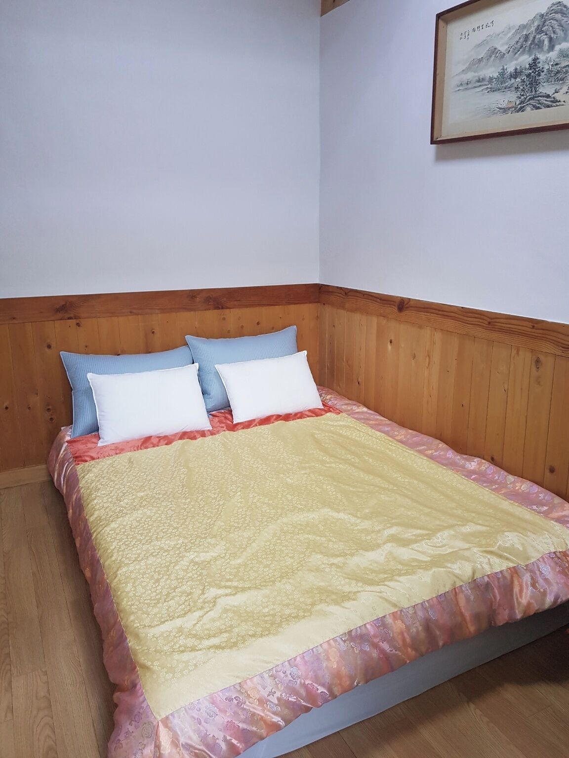 A bed with a wooden headboard, a quilt, and two pillows.