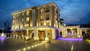 A large, multi-story hotel with a grand entrance, multiple balconies, and a well-lit facade. - The Four Vedas Hotel & Resort (Siliguri)