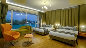 A hotel room with two beds, a sofa, a chair, and a view of a pool. - The Four Vedas Hotel & Resort (Siliguri)