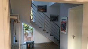 A modern interior with a wooden floor, a staircase with metal railings, and framed pictures on the walls.