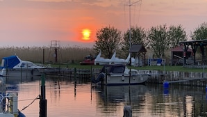 A marina with boats docked, a small building, and a clear sky with the sun setting.