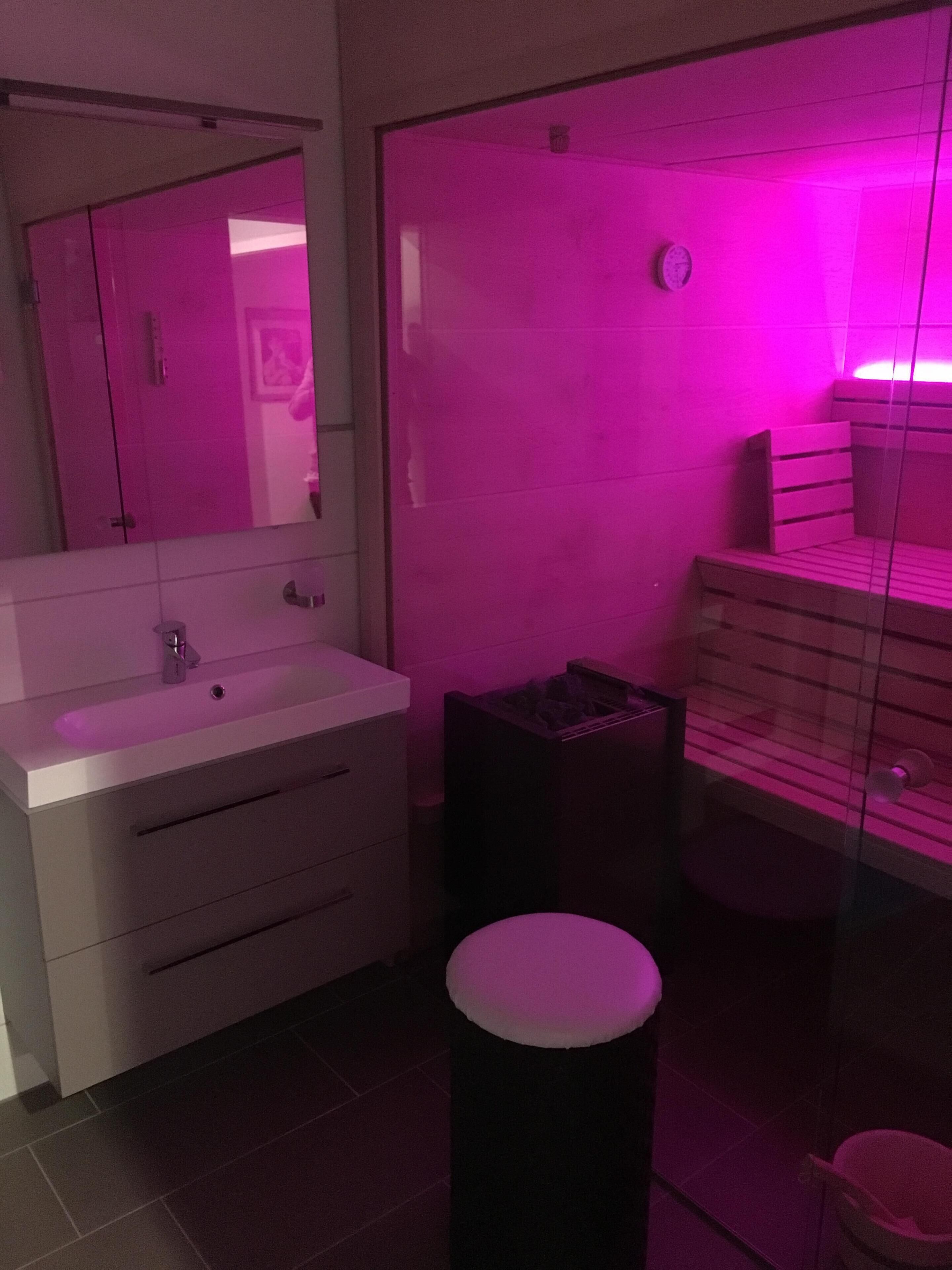 Een moderne badkamer met een wit wastafelmeubel, spiegel en houten onderkast.