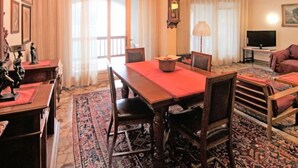 A traditional room with a wooden dining table, chairs, a sofa, and a television. - Lungolago by Interhome (Lavena Ponte Tresa)