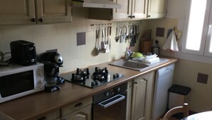 A kitchen with beige cabinets, a microwave, a stove, and a sink. - First floor single house (Querciolo)