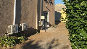 A building with a brown exterior, a narrow entrance, and two air conditioning units. - First floor single house (Querciolo)