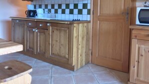 Une cuisine avec des meubles en bois, un four à micro-ondes et un dosseret carrelé.