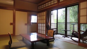 Een traditionele Japanse kamer met tatami vloerbedekking, een lage tafel en twee stoelen.