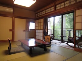 Una habitación japonesa tradicional con suelo de tatami, una mesa baja y dos sillas.